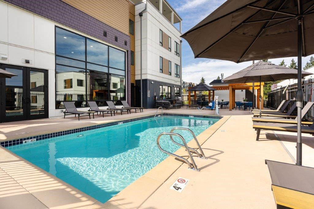 a swimming pool with chairs and umbrellas next to a building