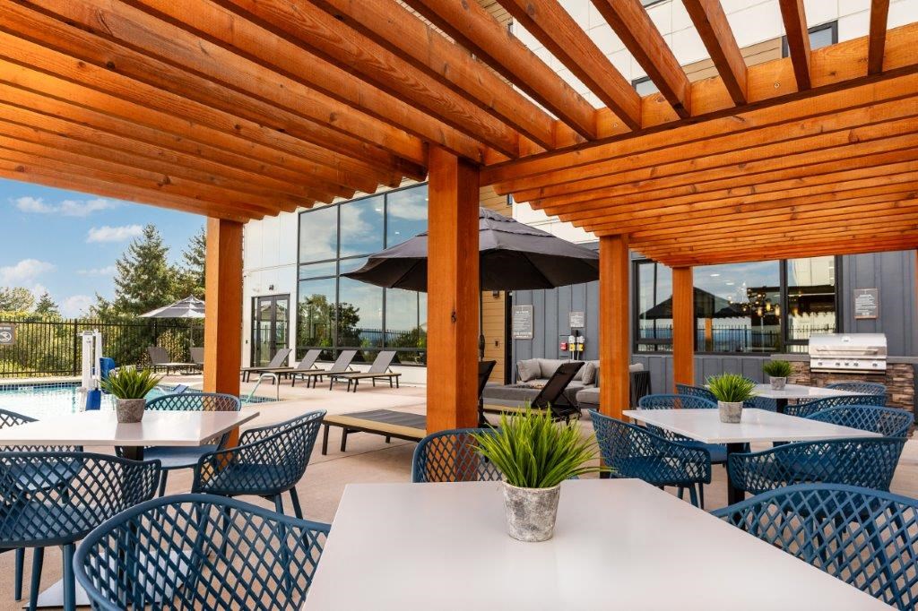 a covered patio with tables and chairs and a pool