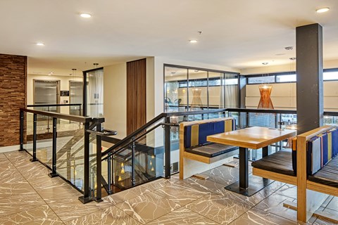 a seating area with tables and chairs in a lobby with a staircase