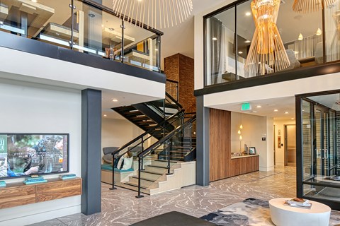 the lobby of a condo with a staircase and a tv