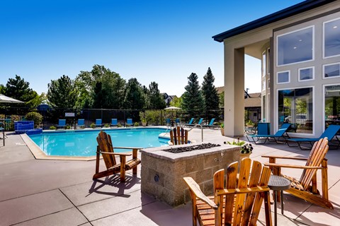 A poolside area with chairs and a stone fireplace.