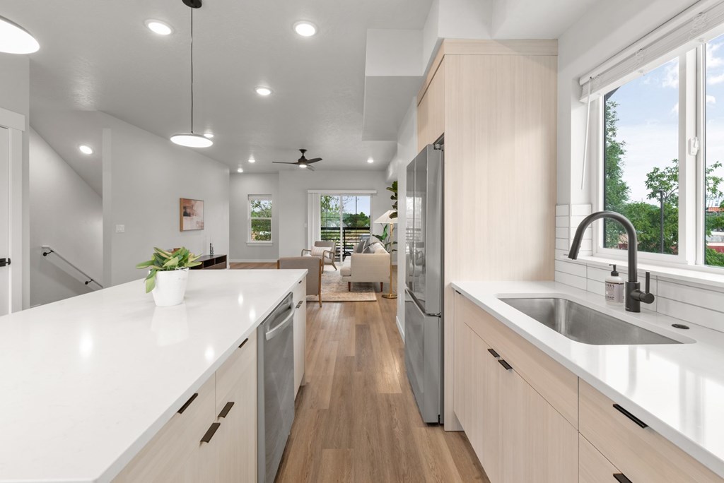 A modern kitchen with a long white countertop and stainless steel appliances.
