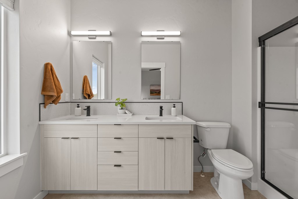 A white bathroom with a toilet, sink, and mirror.