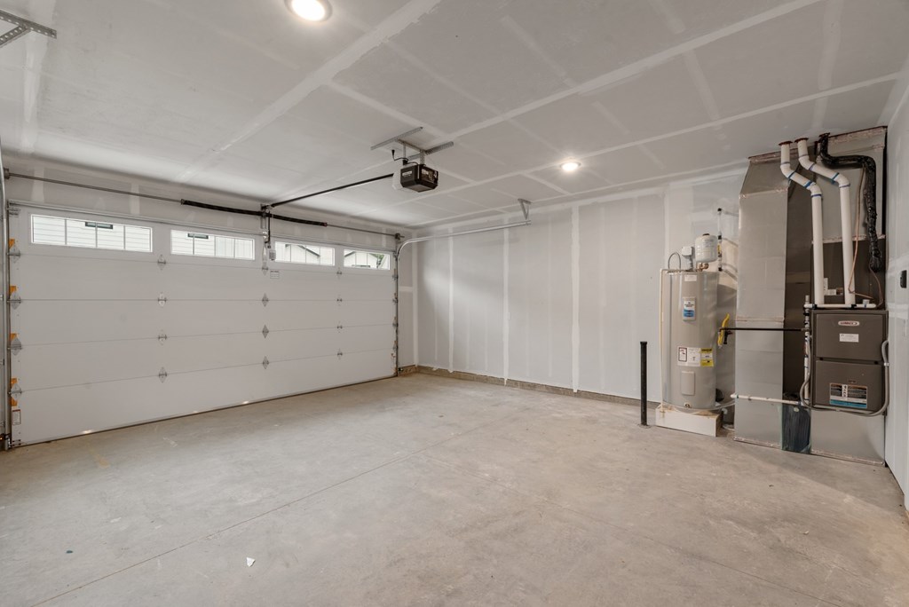 A large, empty room with a garage door on the left and a furnace on the right.