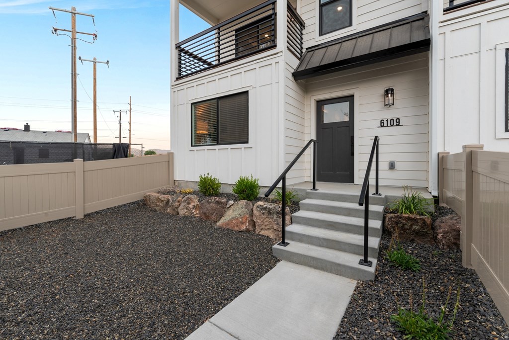 A modern house with a black front door and a gravel driveway.