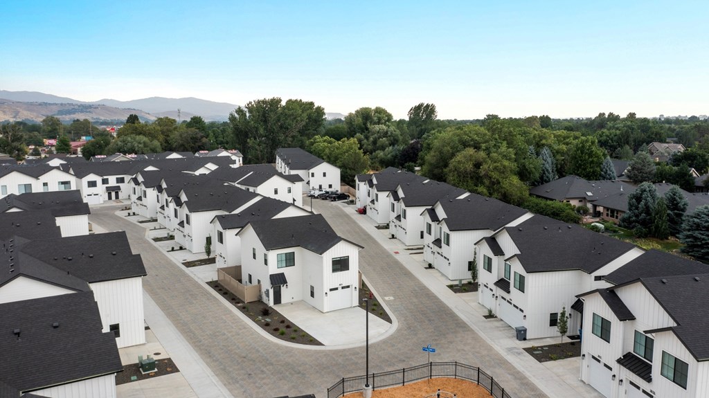 A row of white houses with black roofs are lined up in a residential area.