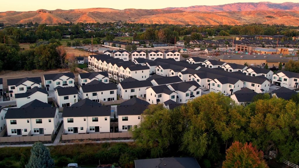 A housing development with white houses and trees in the foreground.