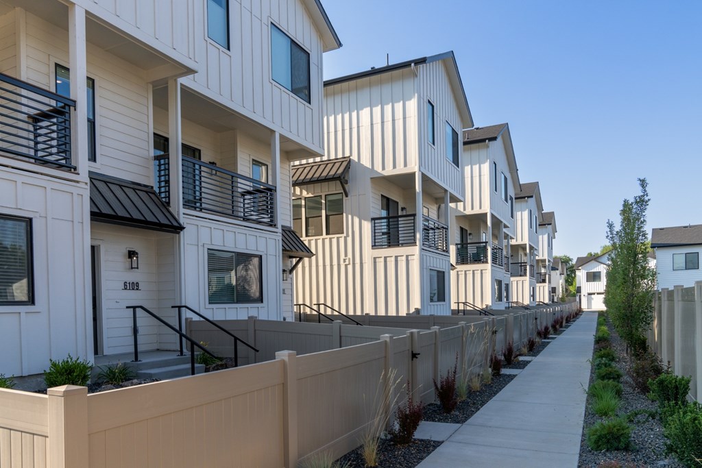A row of white houses with brown fences in front.