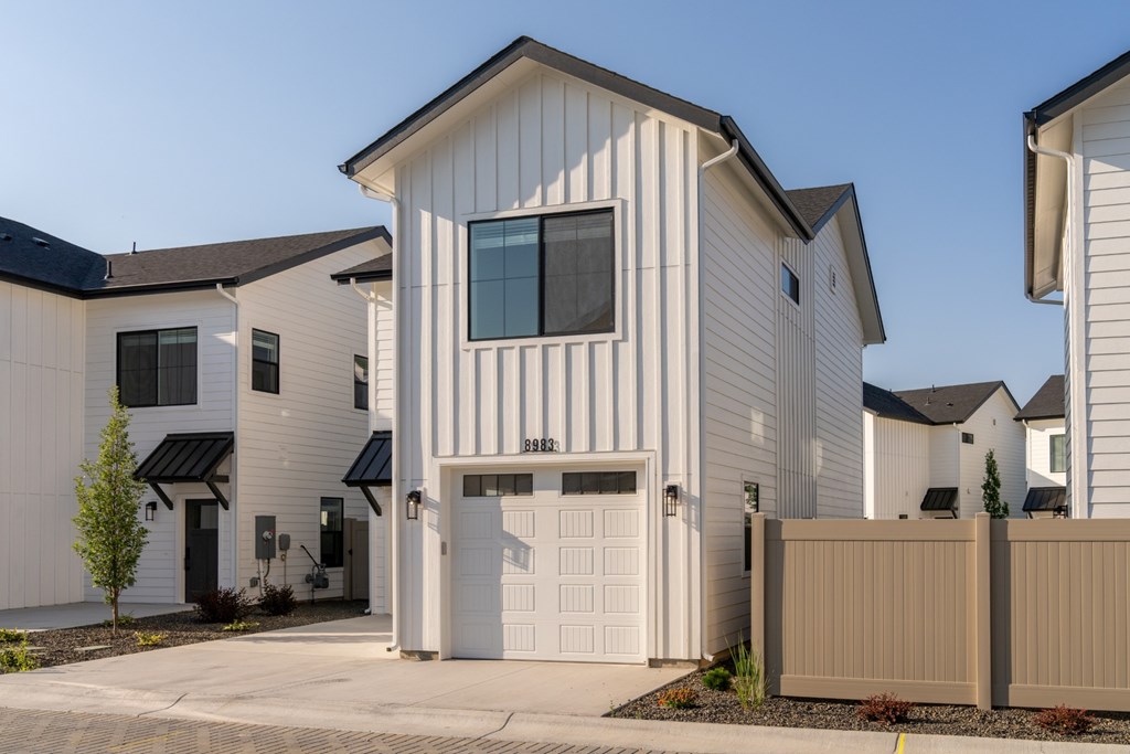A white house with a black roof and a garage door.