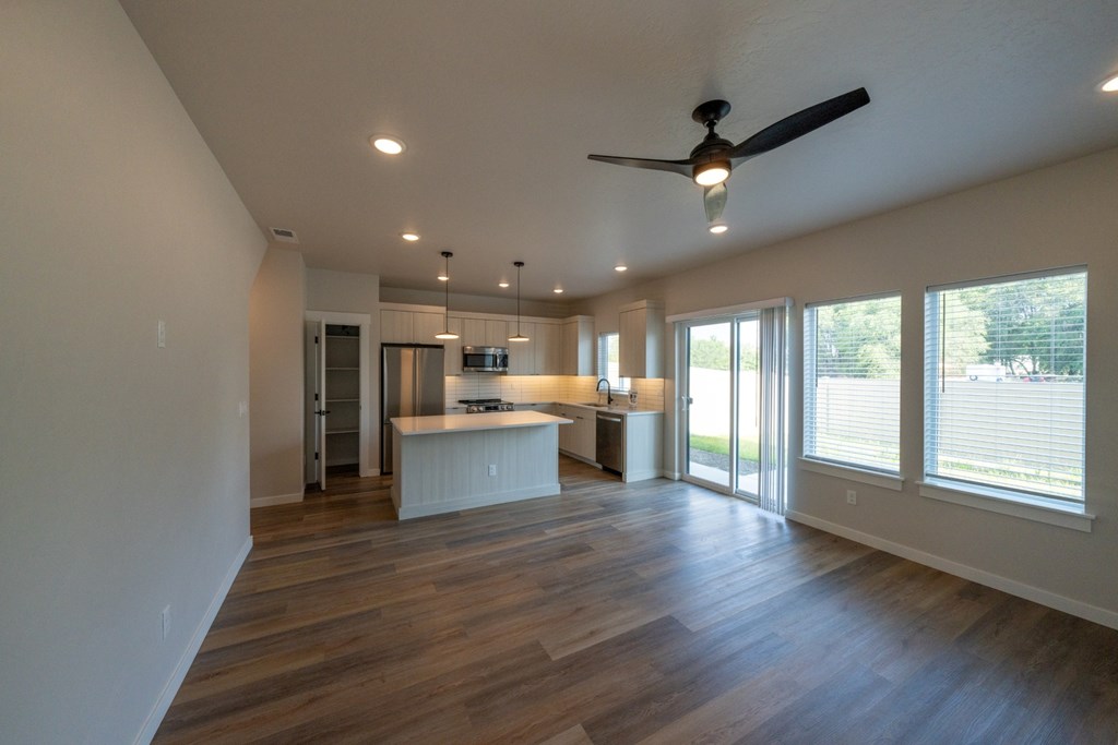 A spacious room with a ceiling fan and wooden flooring.