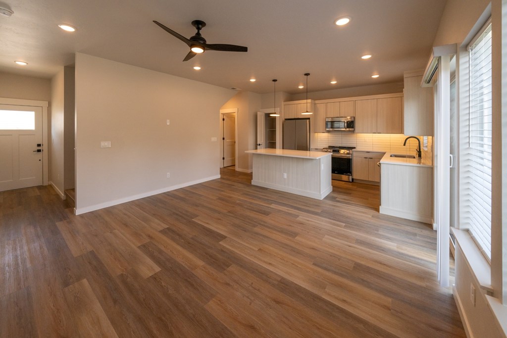 A kitchen with a wooden floor and a ceiling fan.
