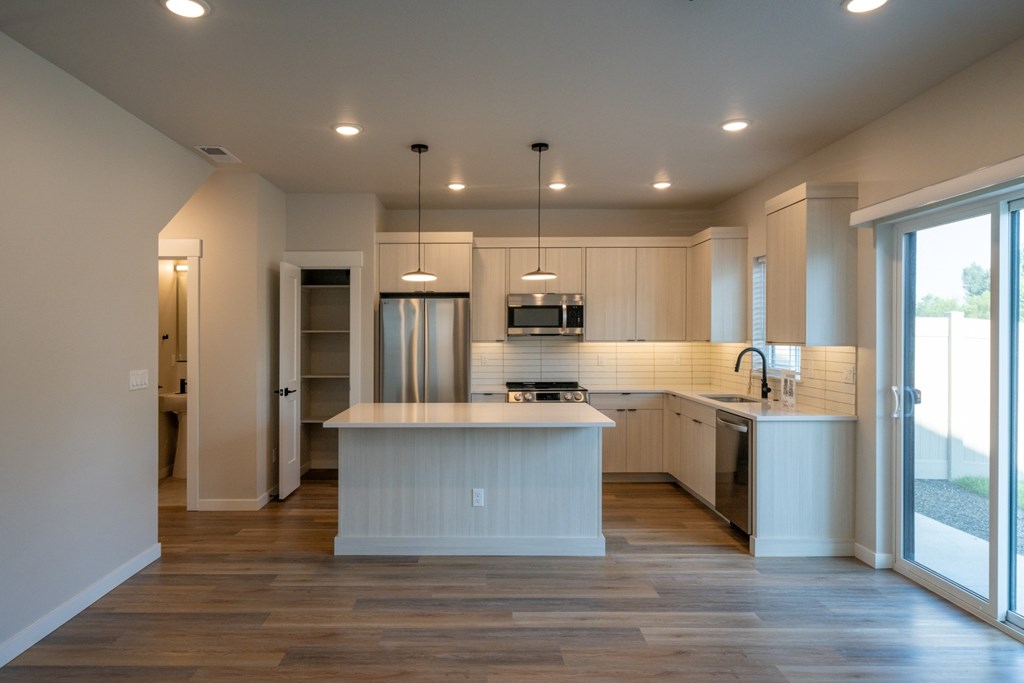 A modern kitchen with a center island and pendant lights.