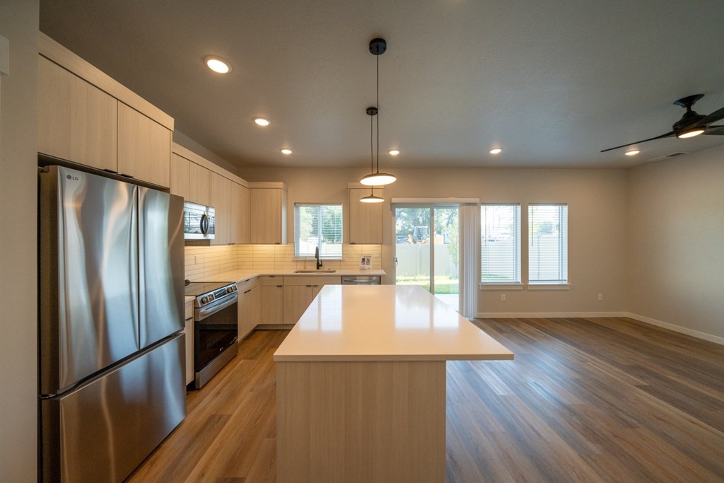 A modern kitchen with wooden floors and stainless steel appliances.
