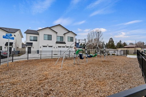 A playground with a swing set and a play area in front of a building.