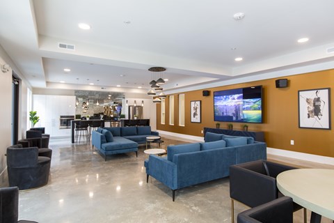 A spacious room with a blue couch and a television on the wall.