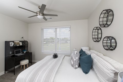 A bedroom with a white bed and a black bookshelf.
