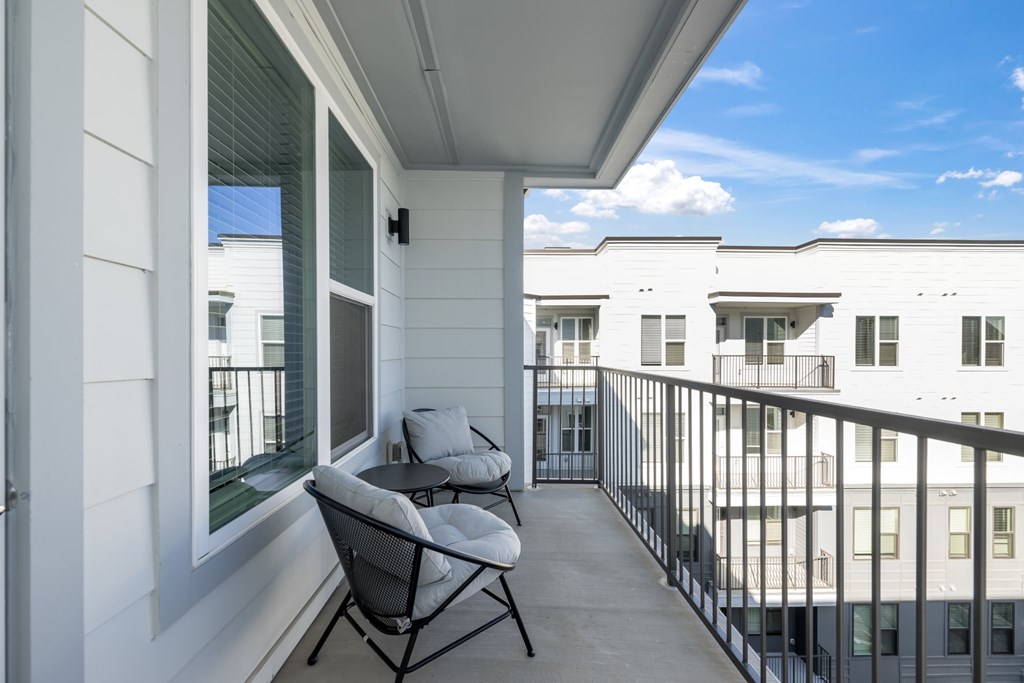 A balcony with a table and two chairs overlooks a building.