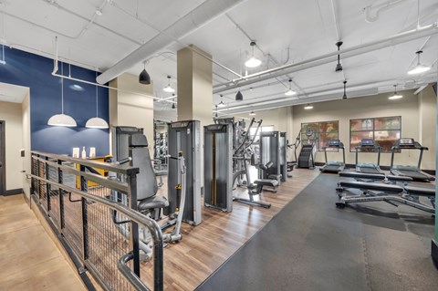 A gym with a variety of equipment including treadmills, weights, and exercise machines.
