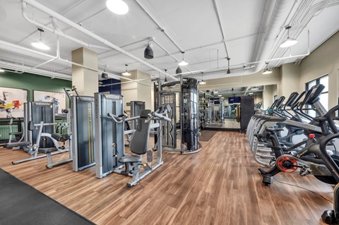 A gym with a variety of equipment including treadmills, weights, and exercise machines.