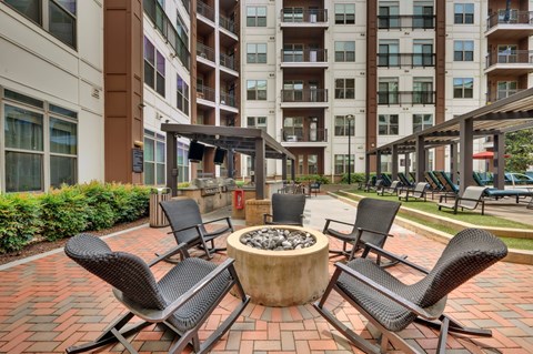 A patio with chairs and a fire pit in front of a building.