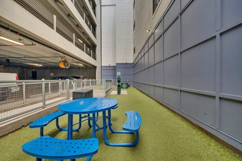 A blue picnic table and bench are in a parking garage.