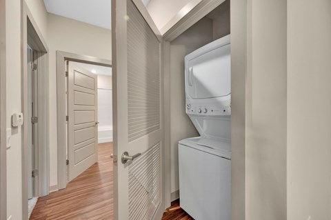 A white washing machine is in a narrow hallway.