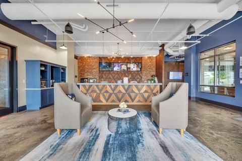 A modern office lobby with a blue carpet and a wooden patterned wall.