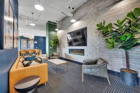 A modern office space with a yellow sofa, a grey armchair, and a potted plant.