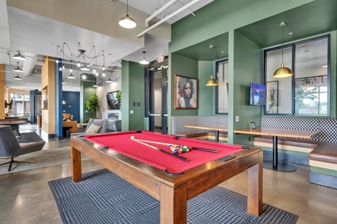 A pool table is in the middle of a room with a green wall.