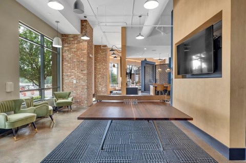A room with a long table and chairs in front of a brick wall.