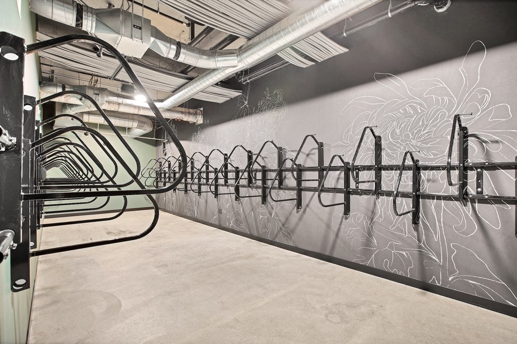 A row of black metal racks in a room with a large black and white mural on the wall.