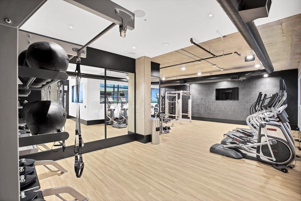 A gym with a variety of exercise equipment including treadmills, weights, and exercise machines.