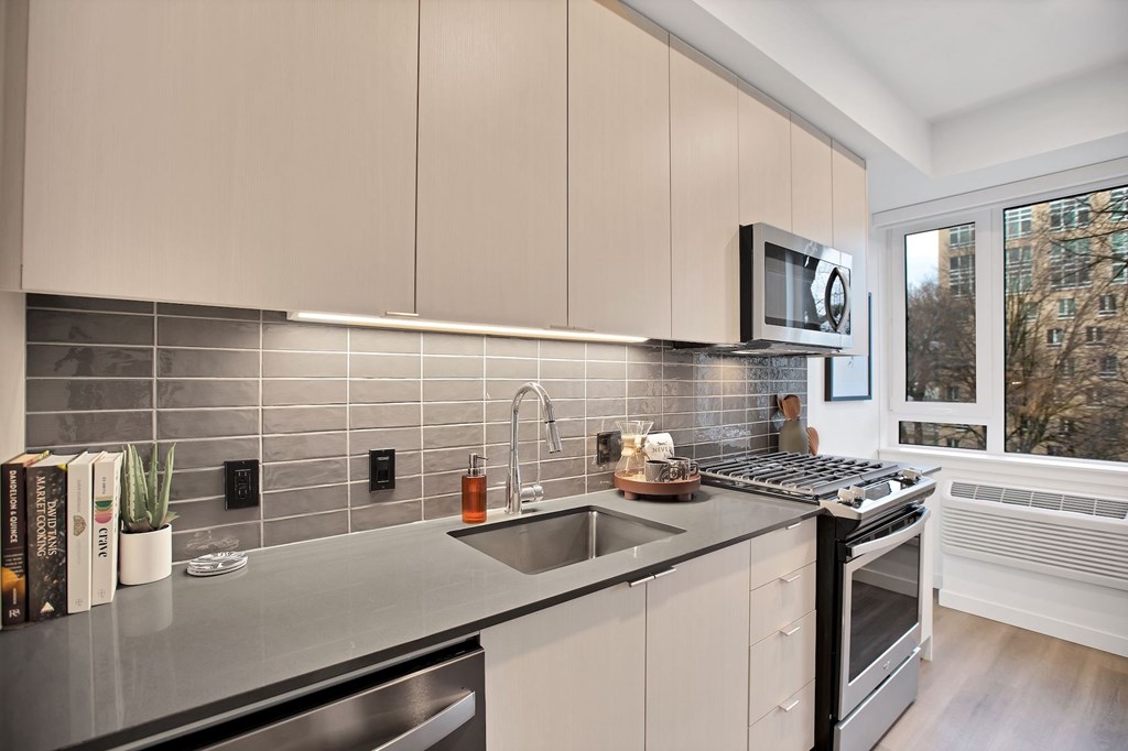A modern kitchen with a stainless steel sink and black oven.