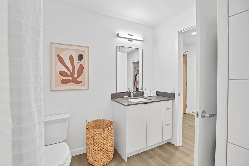 A bathroom with a white toilet, a brown basket, and a white sink.