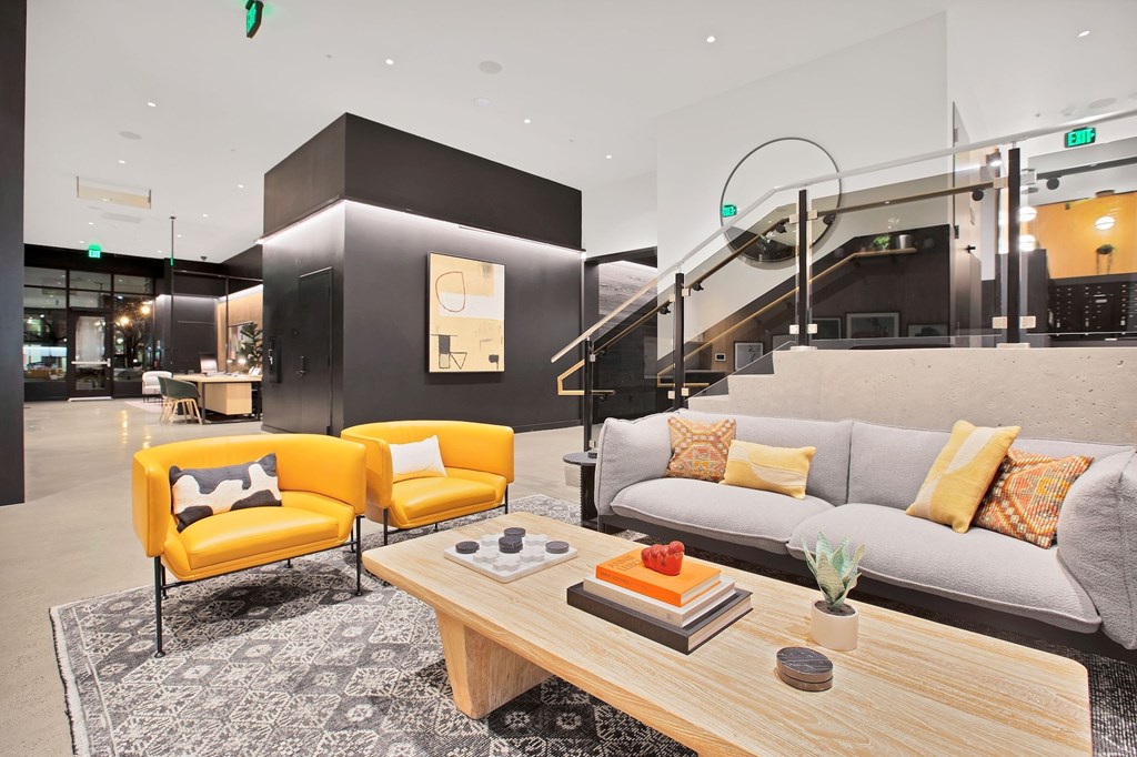 A modern living room with a grey couch, yellow chairs, and a wooden coffee table.