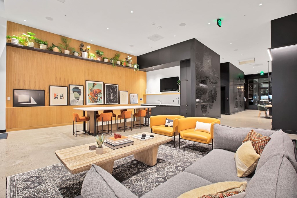 A modern living room with a grey sofa, a wooden coffee table, and a wall with framed pictures.