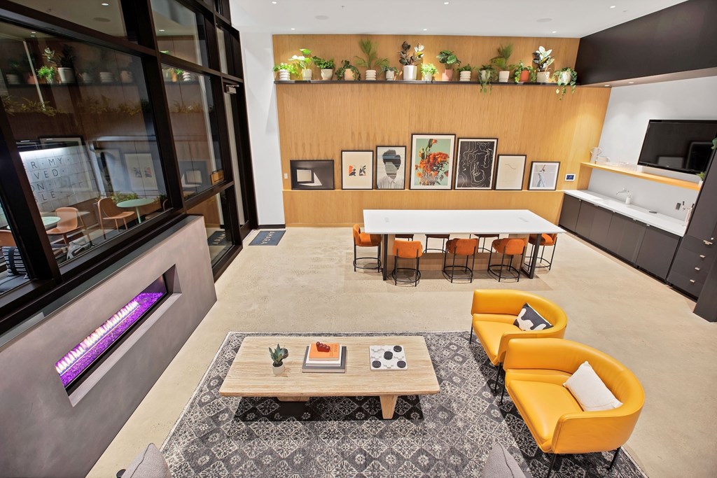 A modern living room with a large window, a coffee table, and a row of orange chairs.