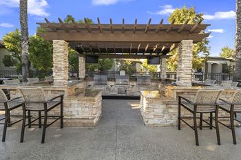 a patio with a stone fireplace and a pergola