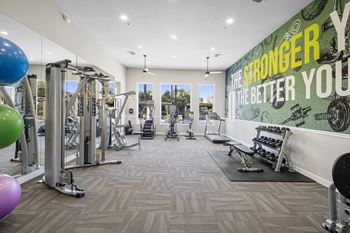 a gym with weights and cardio equipment and a mural on the wall