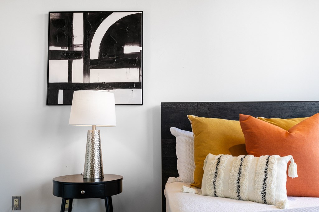 a bedroom with a bed with orange pillows and a table with a lamp