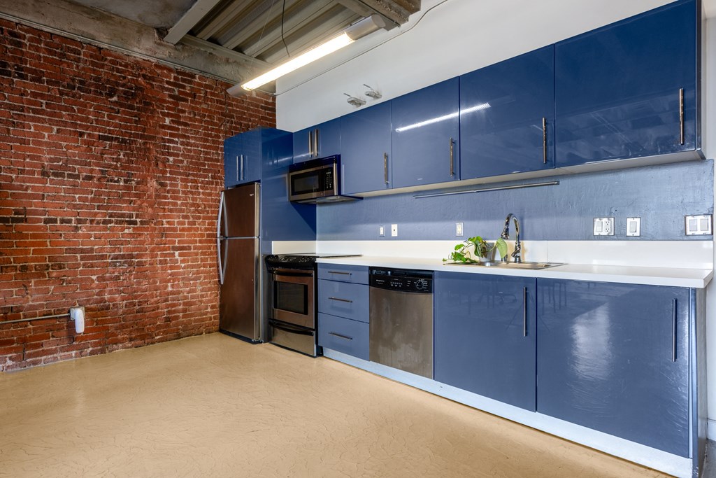a kitchen with blue cabinets and a brick wall