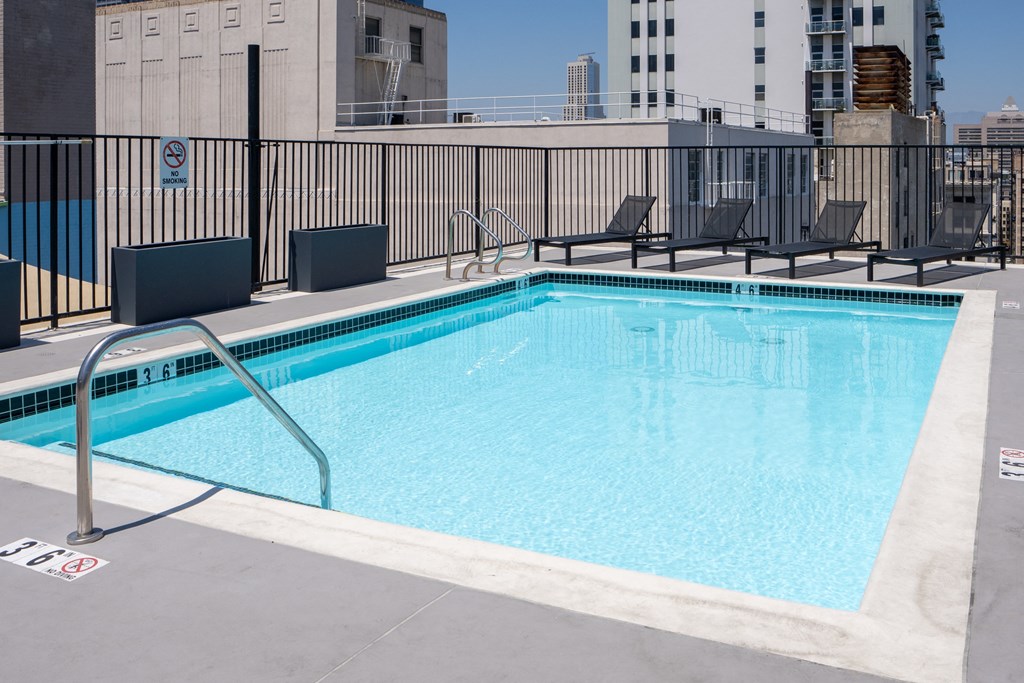 a swimming pool on the roof of a building with chairs