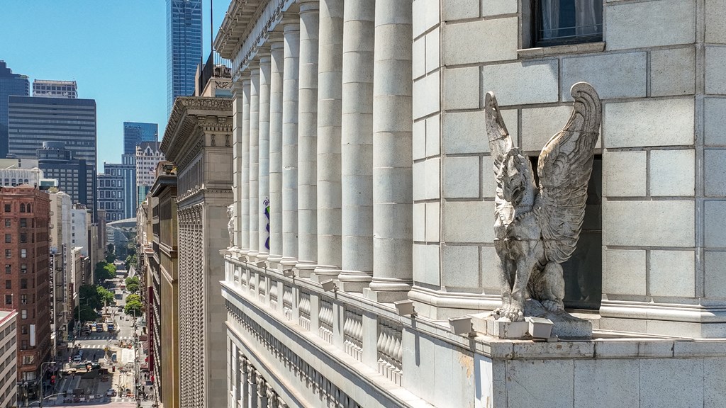 a statue of an eagle on the side of a building overlooking a city street