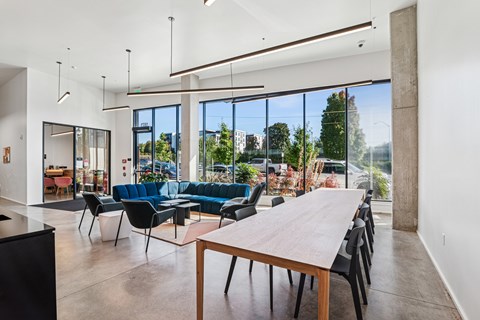 A modern living room with a long wooden table and black chairs.