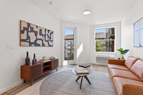 A living room with a brown couch, a wooden table, and a painting on the wall.