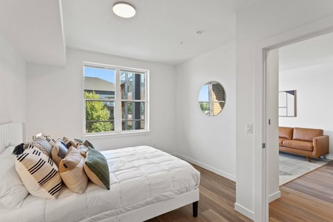 A bedroom with a large bed and a window overlooking a green area.