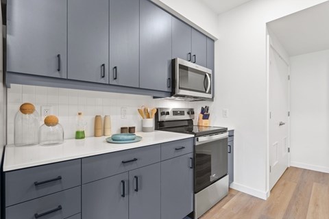 A kitchen with grey cabinets and a white countertop.