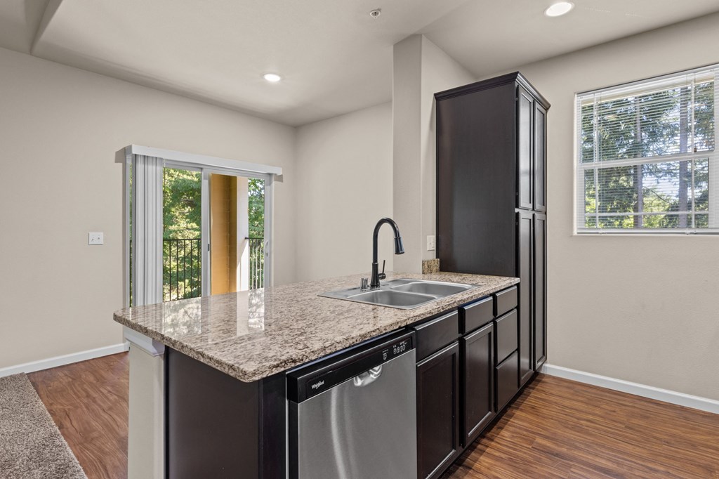 Little Tuscany Apartments & Townhomes - Kitchen Cabinets with Dark Color, Stainless Steel Appliances, Vinyl Wood Plank Flooring, White Woodwork, Granite Countertops, Breakfast Bar