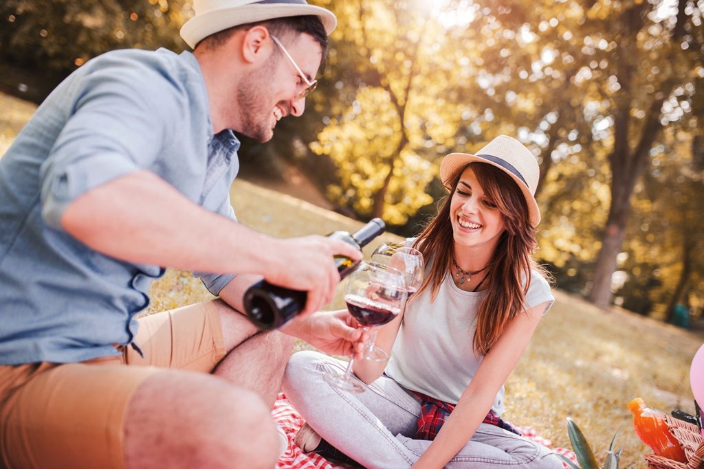 Man and Woman Smiling while Having Picnic and Drinking Wine