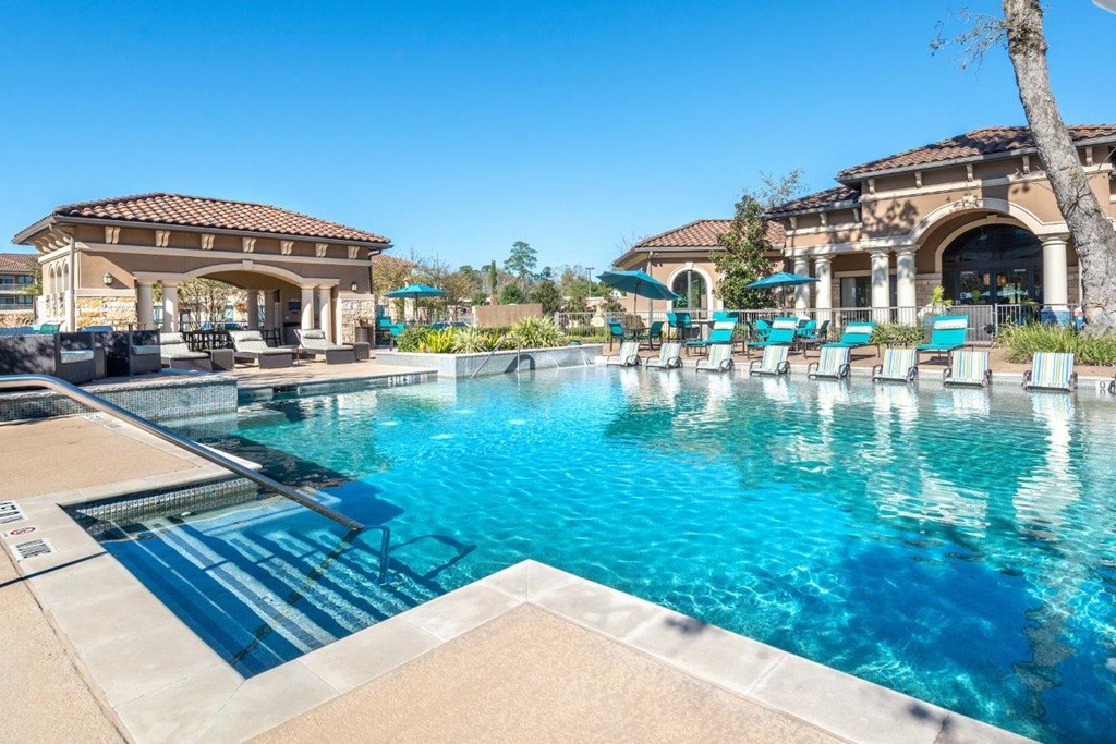 a swimming pool with lounge chairs and umbrellas